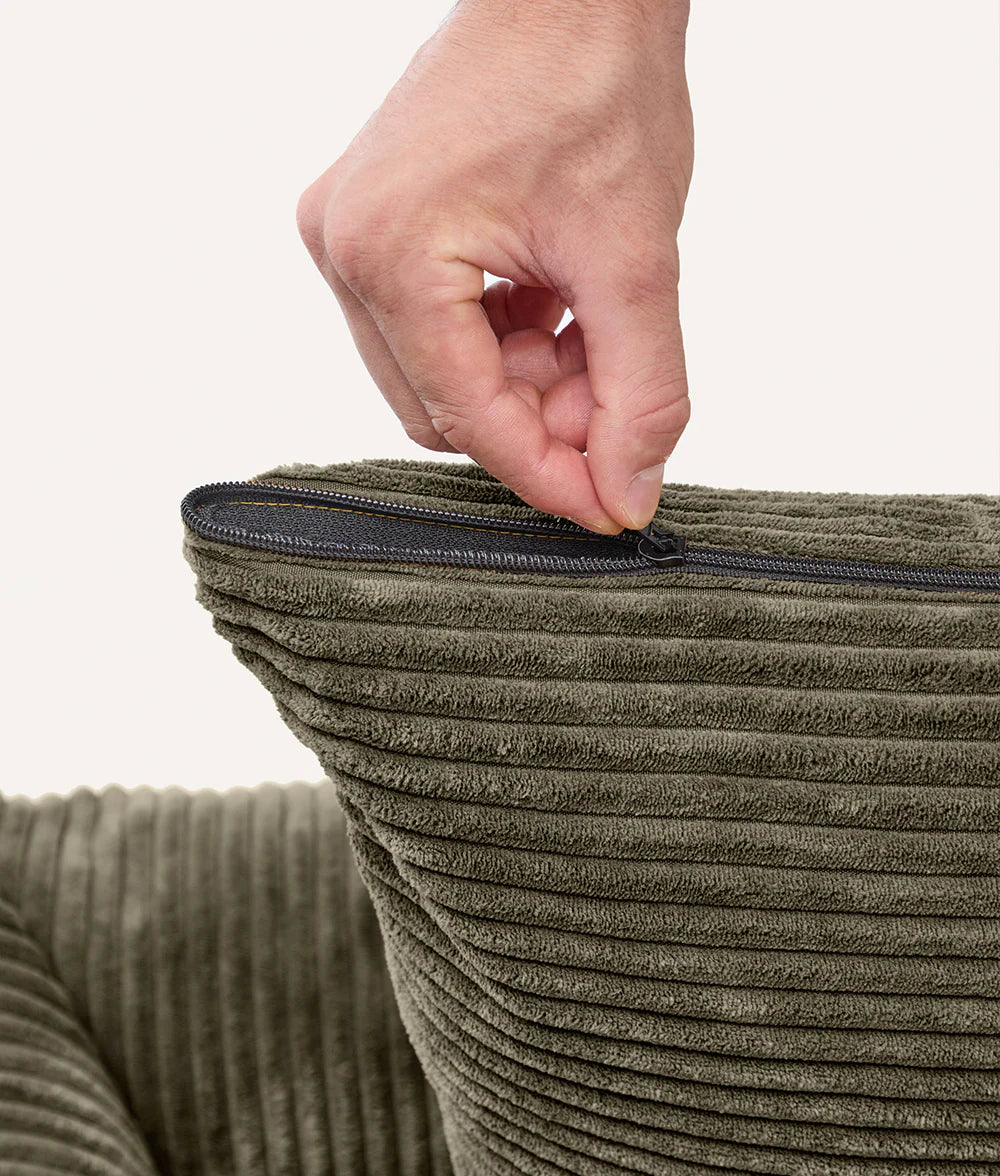 Hand zipping a green textured bag against a white background