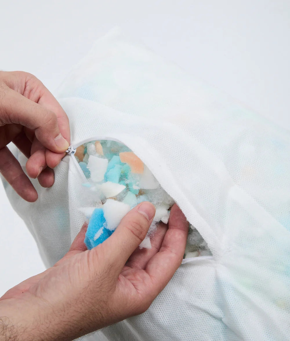 Person adjusting colorful gel packs in a pillow with a white background