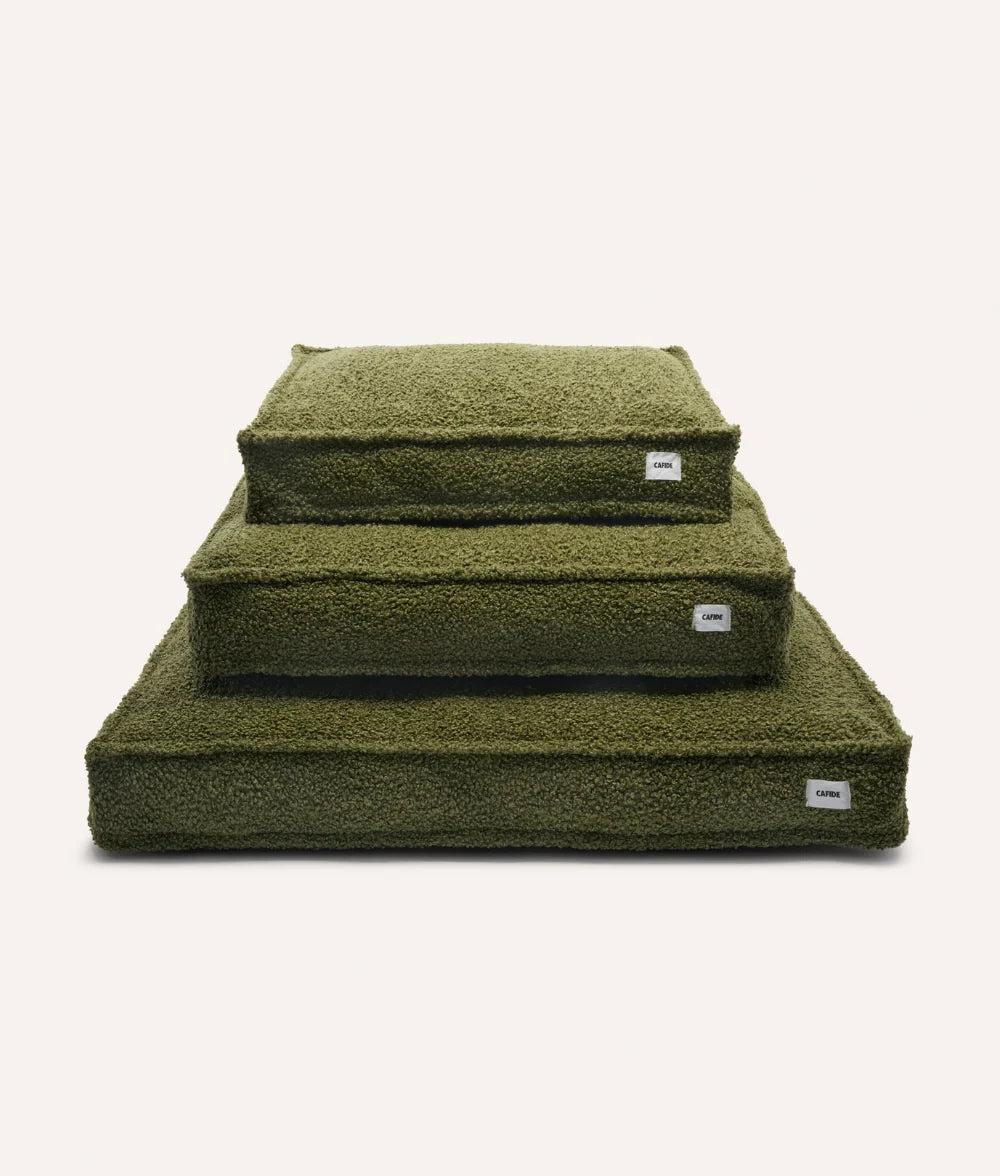 Set of three green pet beds stacked on a white background