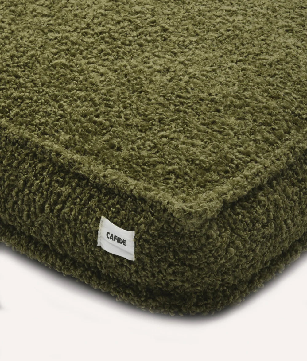 Green textured cushion with a visible brand label on a white background