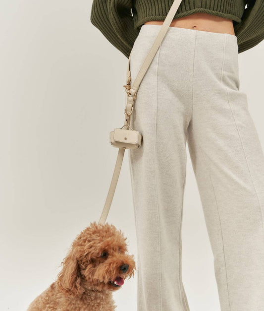 Person wearing light gray pants with a beige strap over a white background