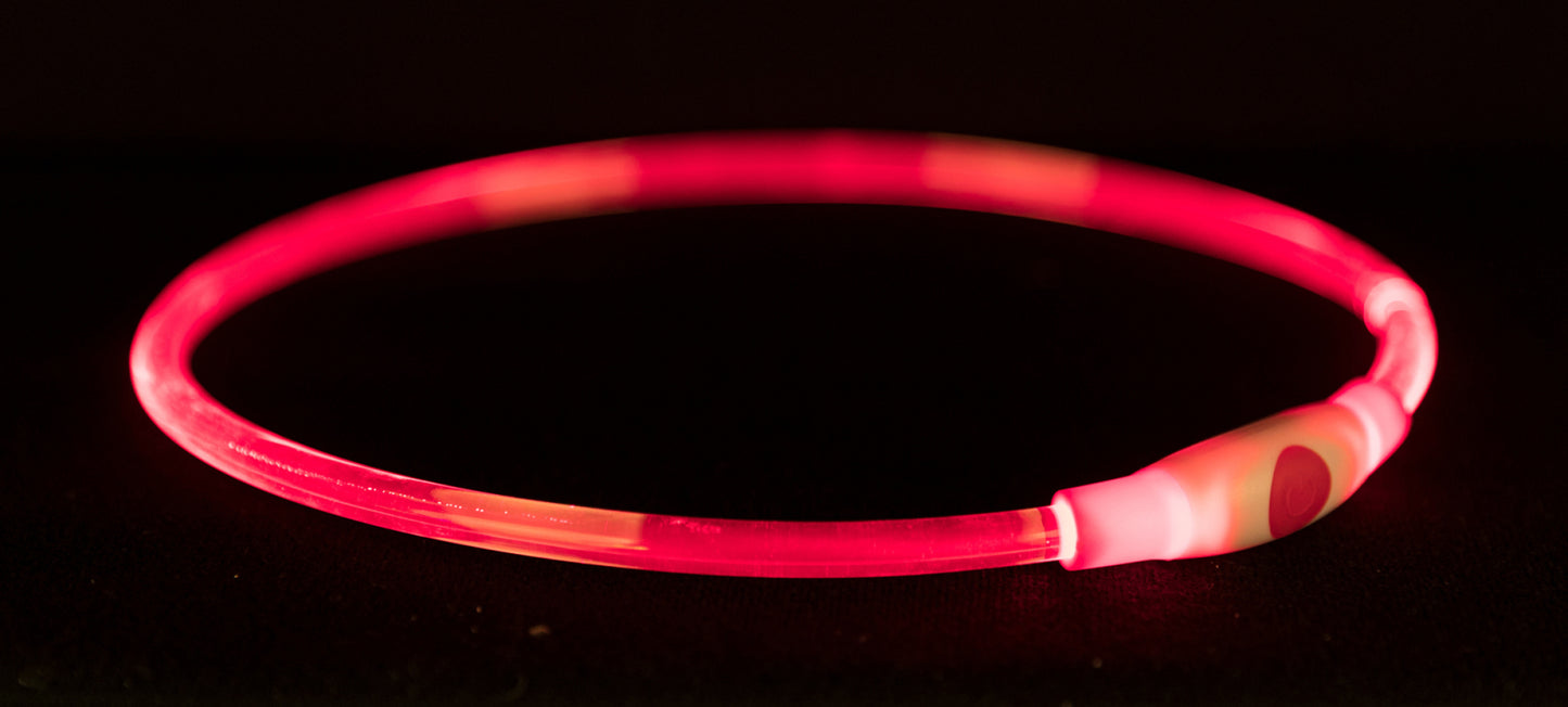Pink and red striped glowing bracelet on a black background