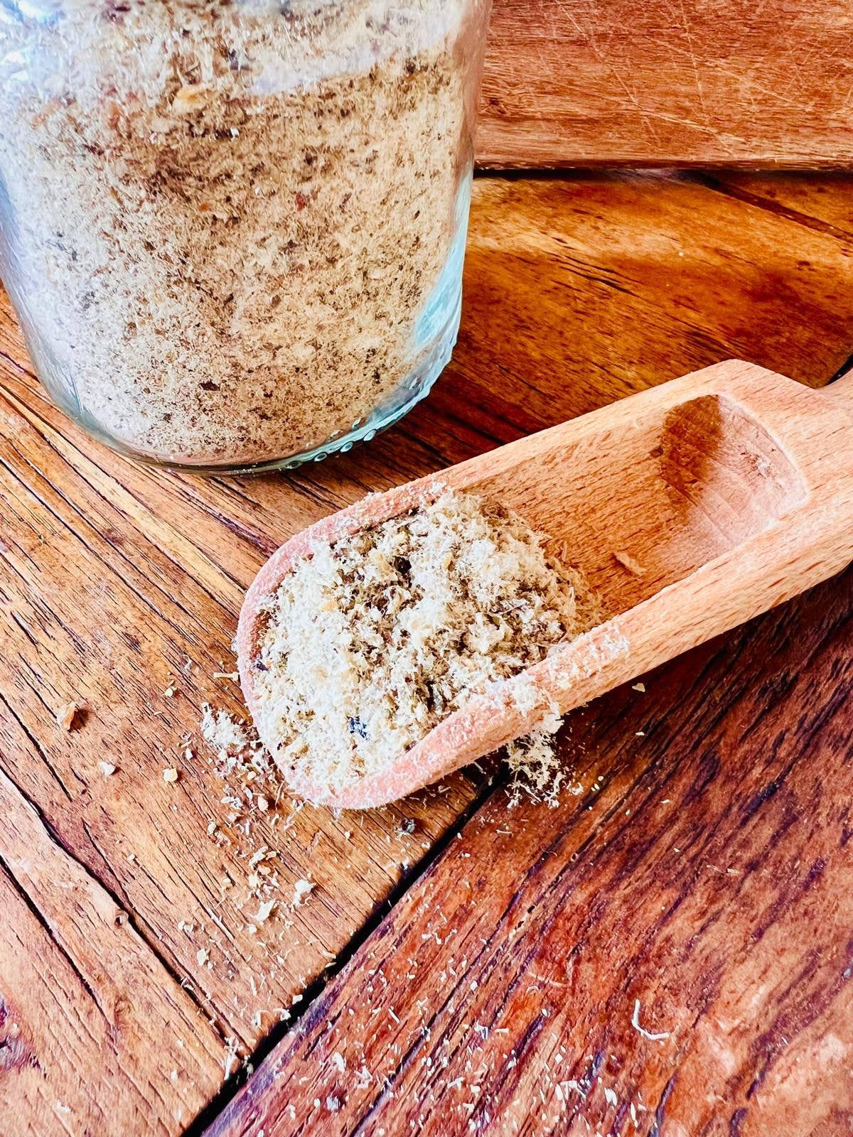 Wooden scoop filled with a spice mix on a wooden surface