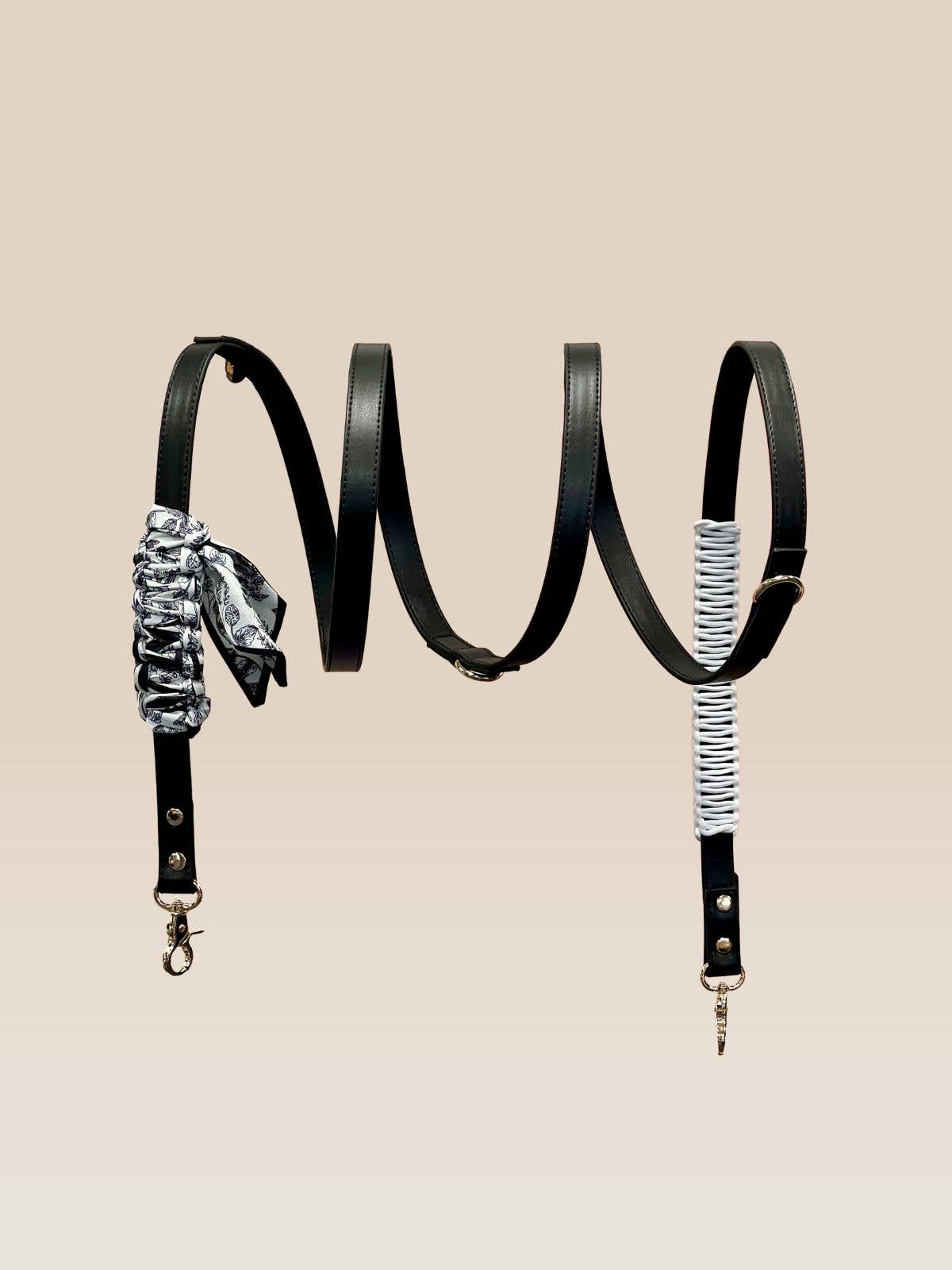 Black leather bag strap with decorative elements on a beige background