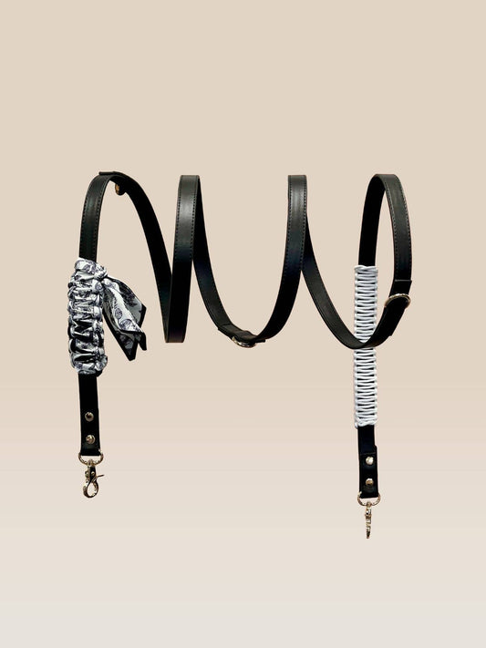 Black leather bag strap with decorative elements on a beige background