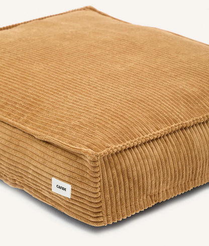 Brown ribbed cushion with a visible brand label on a white background