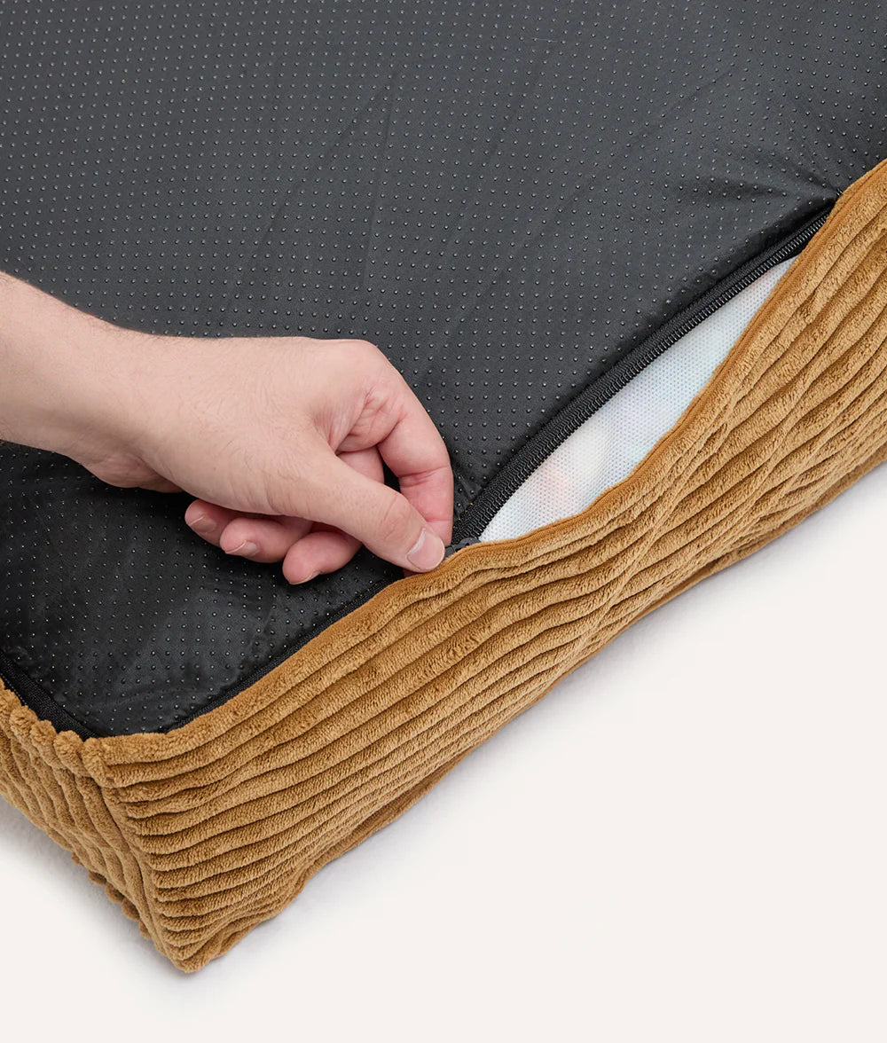 Person holding a black mattress cover with brown trim on a white background