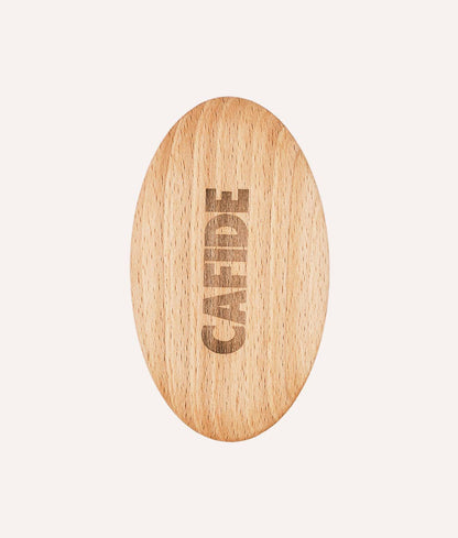 Wooden oval object with 'CAFIDE' engraving on a light beige background