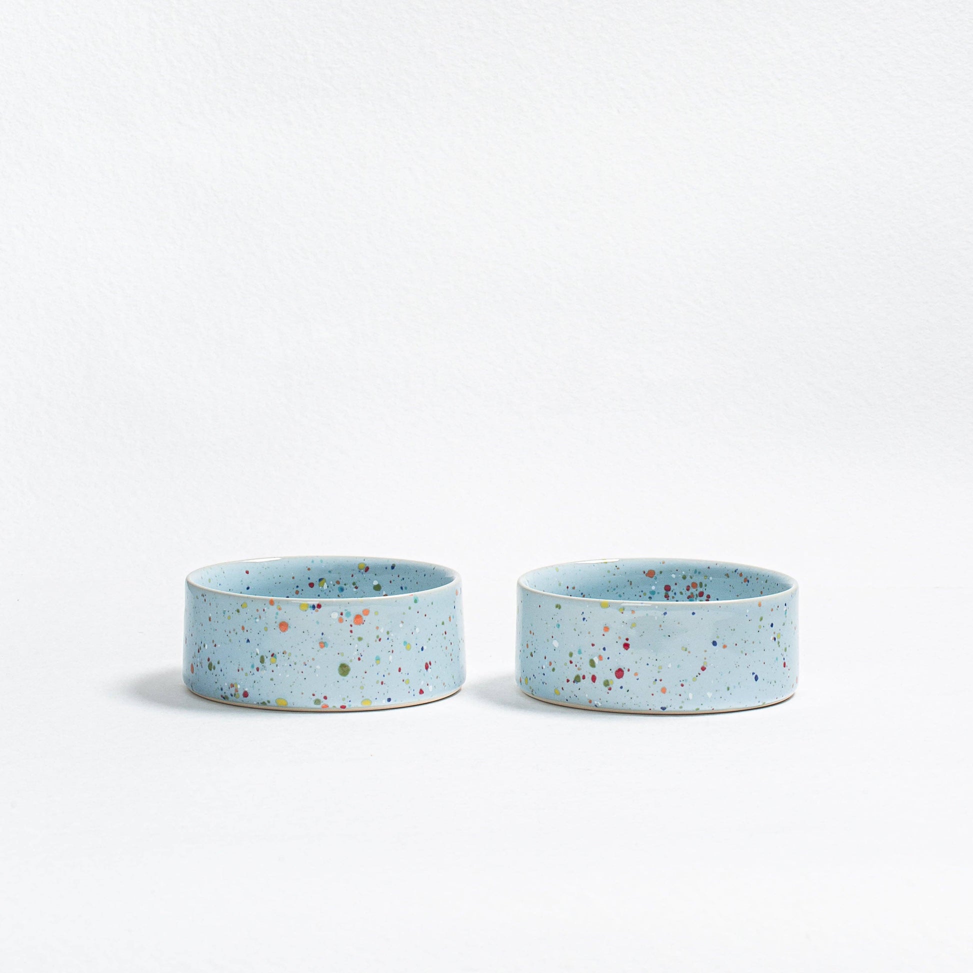 Two small blue ceramic bowls with speckled pattern on a white background