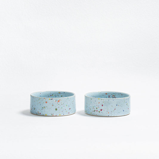 Two small blue ceramic bowls with speckled pattern on a white background