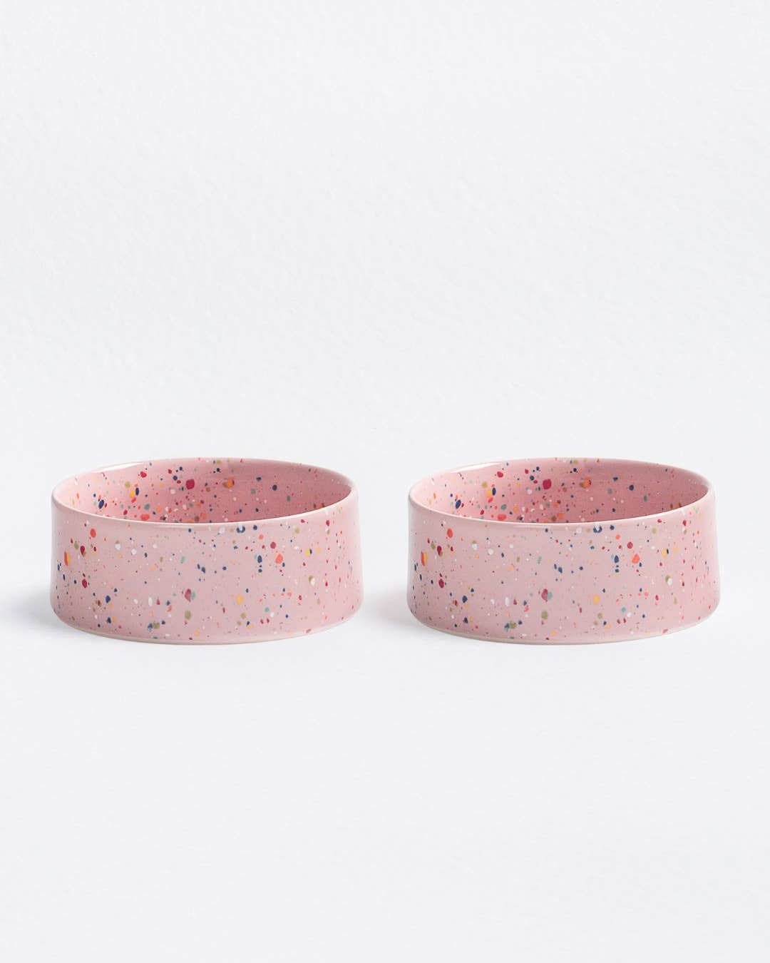 Two pink bowls with speckled pattern on a white background