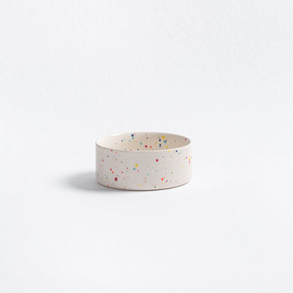 White ceramic bowl with colorful speckles on a light gray background