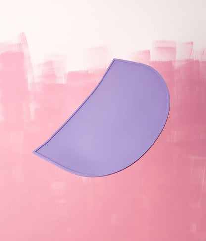 Purple half-circle silicone mat on a pink textured background