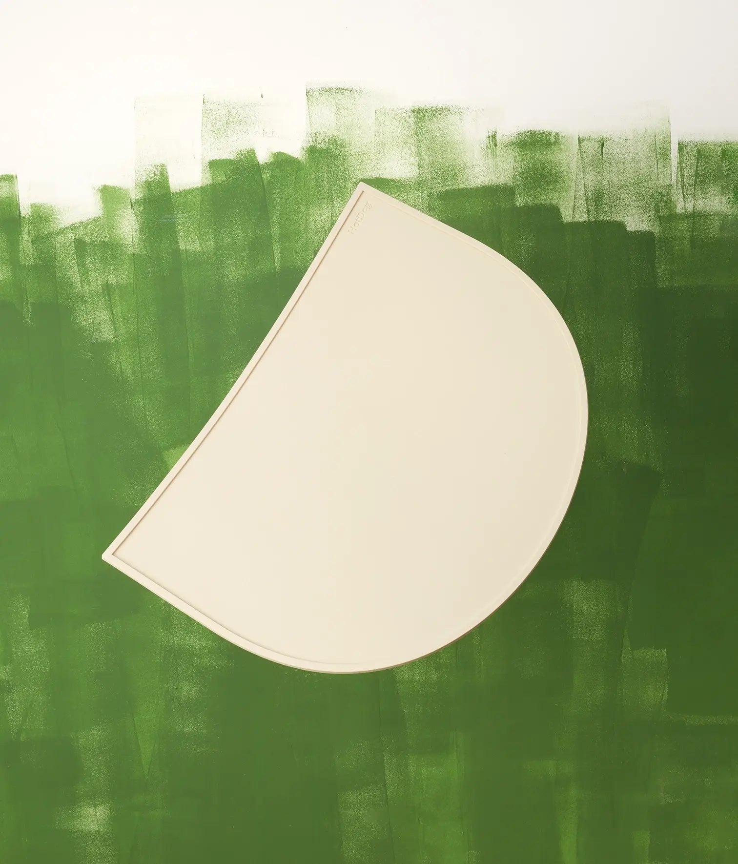 Abstract art with a beige semi-circle shaped silicone mat on a textured green background