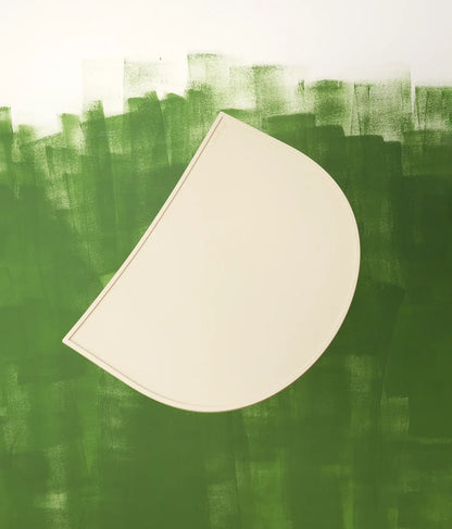 Abstract art with a beige semi-circle shaped silicone mat on a textured green background
