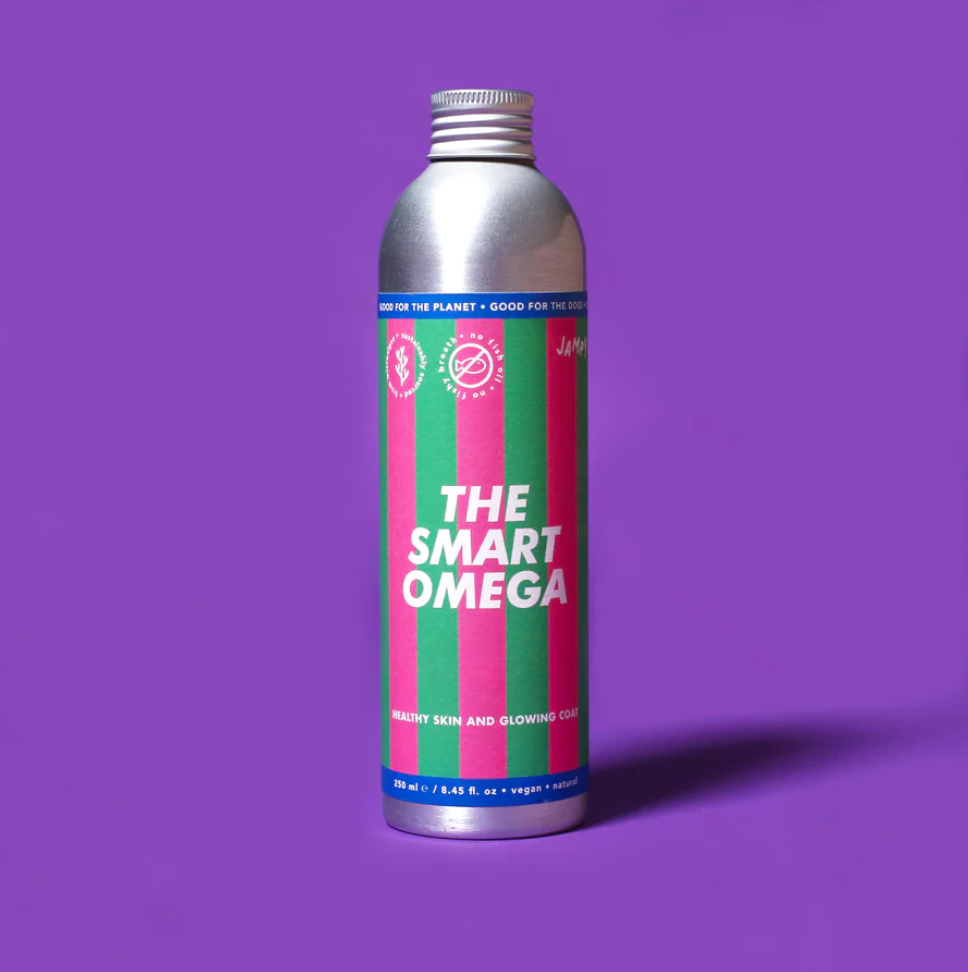 A silver aluminum spray bottle of 'The Smart Omega' hair product, featuring a colorful label with vertical pink and green stripes and white text, set against a solid purple background.