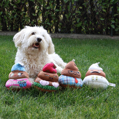 White dog sitting on grass with poop-shaped plush toys in front of it