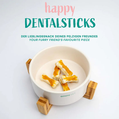 Bowl with dog treats labeled 'happy DENTALSTICKS' on a white background