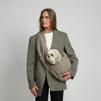 Woman holding a dog in a coat with a pocket, on a plain background