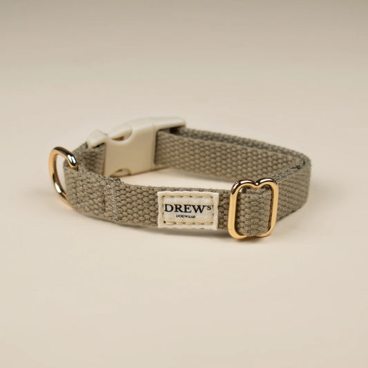 Dog collar with gold buckle and 'Drew' label on a beige background