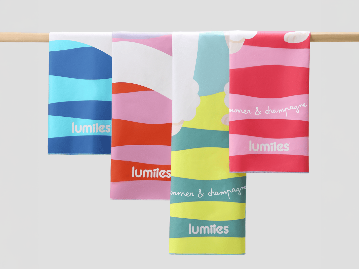Four colorful striped towels hanging on a rod with 'lumities' branding.