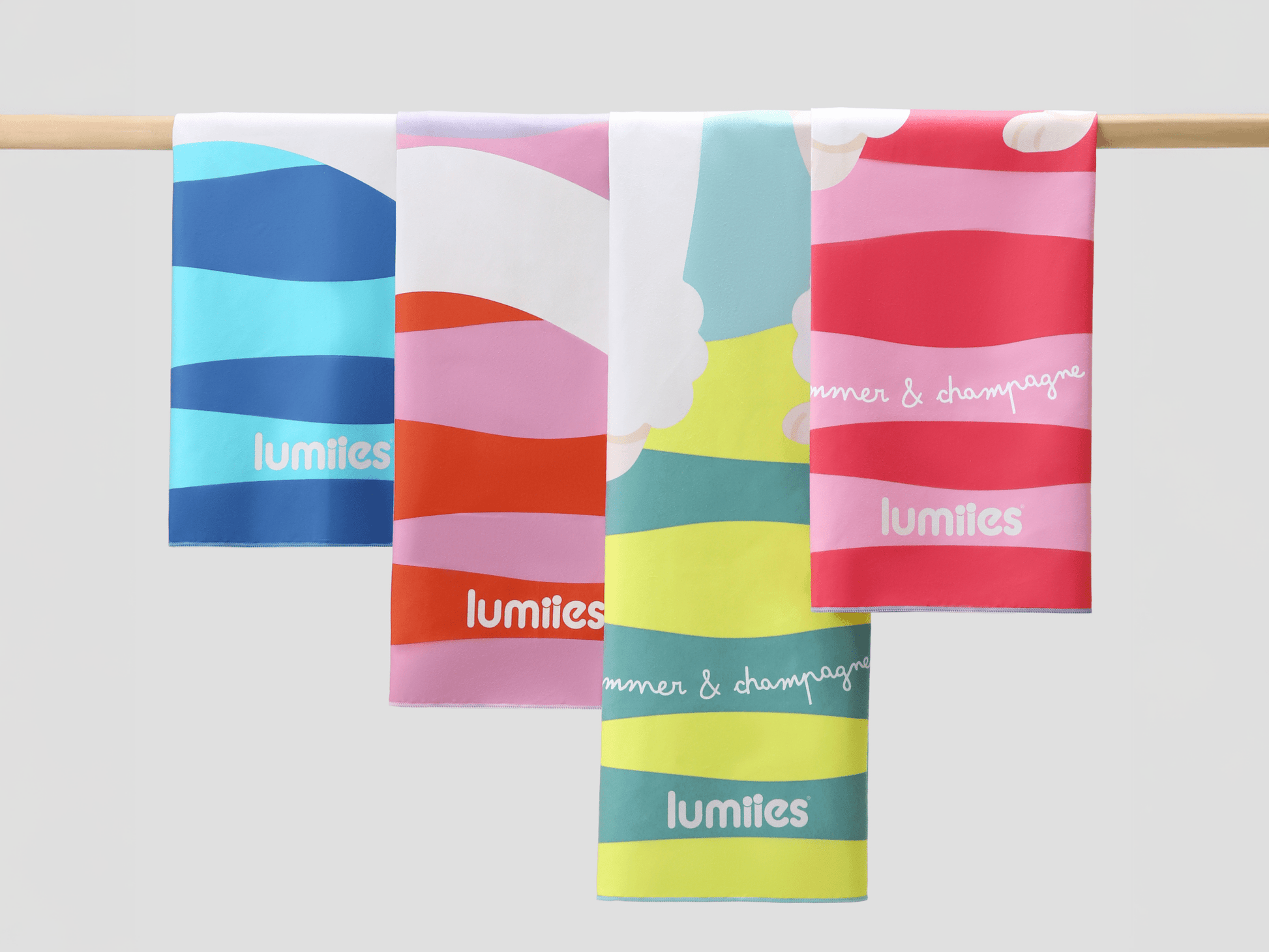 Four colorful striped towels hanging on a rod with 'lumities' branding.