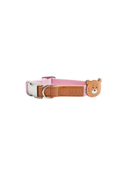 A pink fabric dog collar with a tan leather strap, silver buckle, and a small 3D bear head charm on the side.