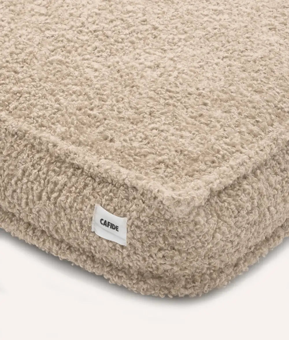 Beige pet bed with a visible brand label on a white background