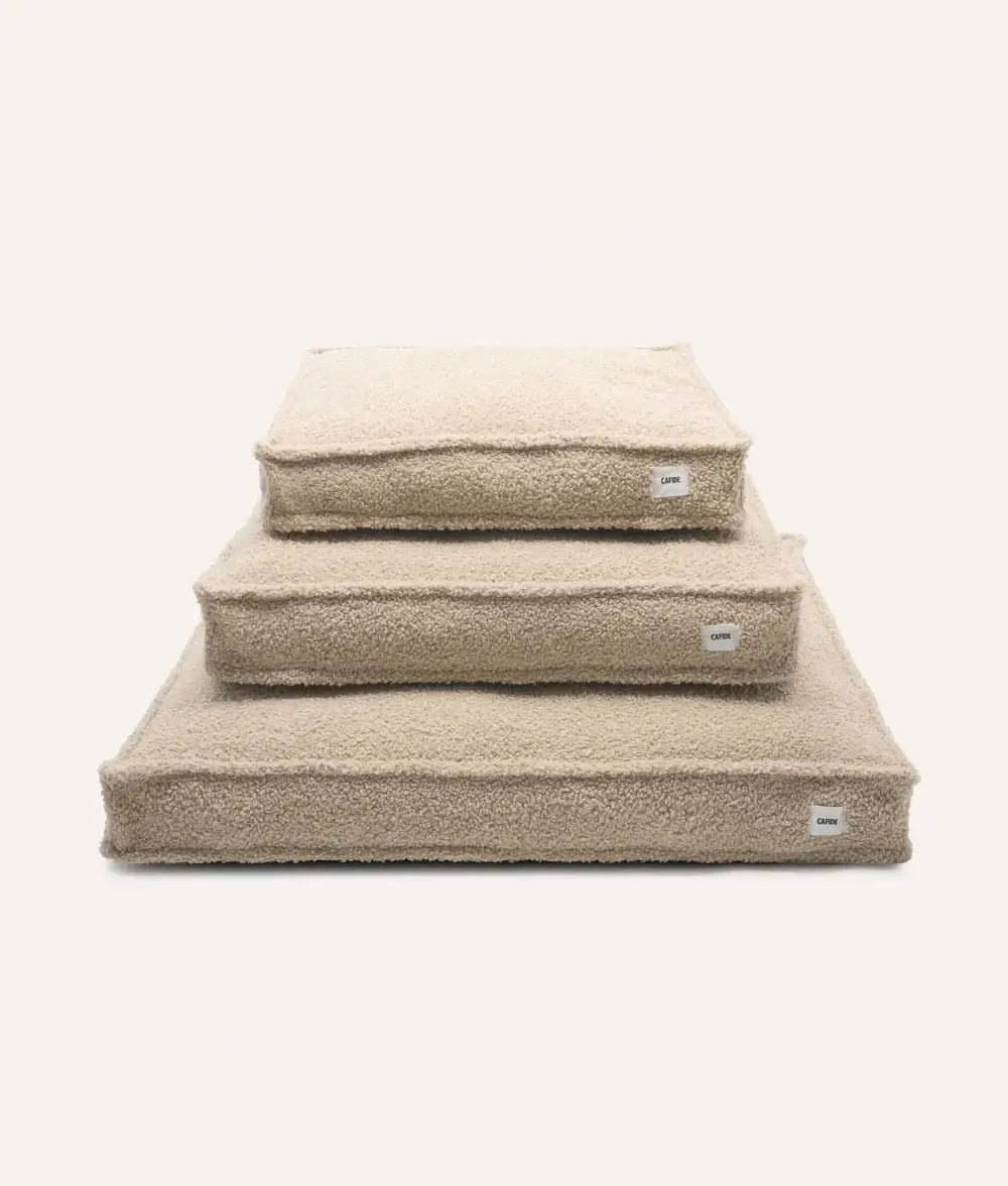 Set of three beige pet beds stacked on a white background