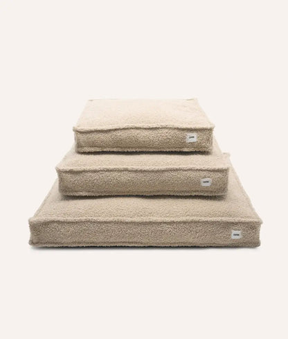 Set of three beige pet beds stacked on a white background