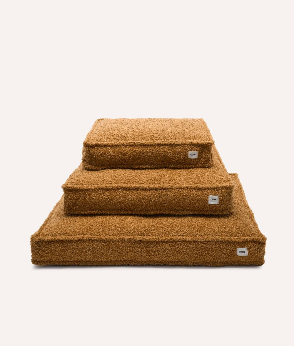 Three stacked brown pet beds on a white background