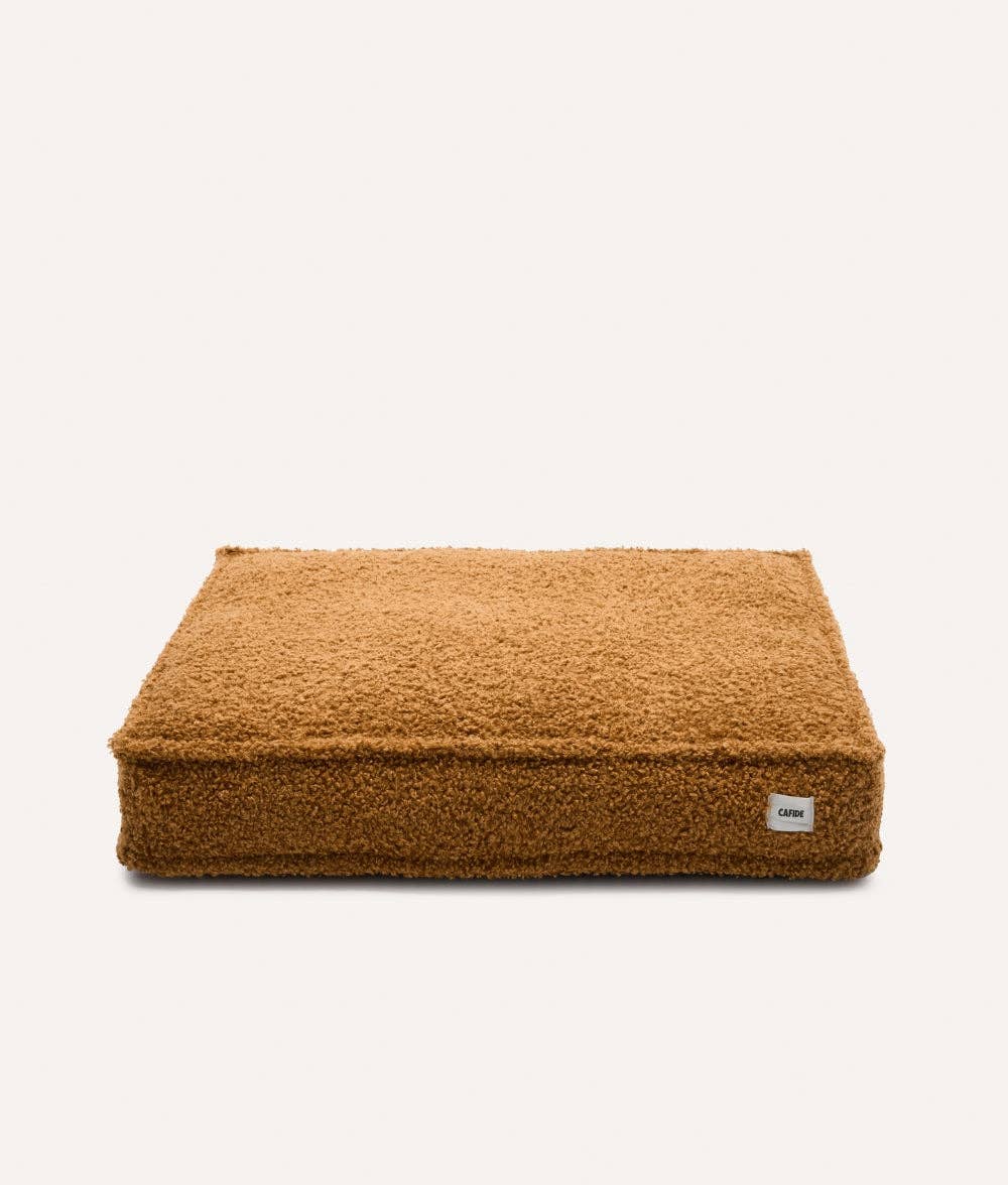 Brown pet bed with a visible brand label on a white background