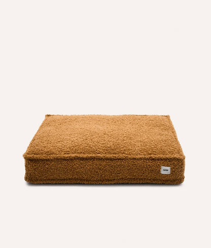 Brown pet bed with a visible brand label on a white background