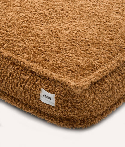 Brown textured cushion with a visible brand label on a white background