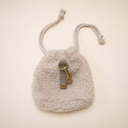 Small fluffy pouch with a drawstring and gold clasp on a beige background